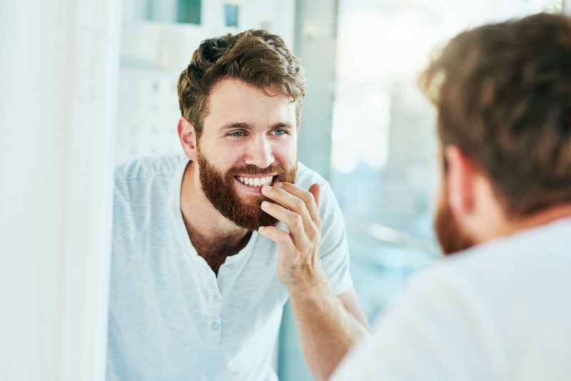 man admiring his teeth in the mirror after visiting Solar Dental